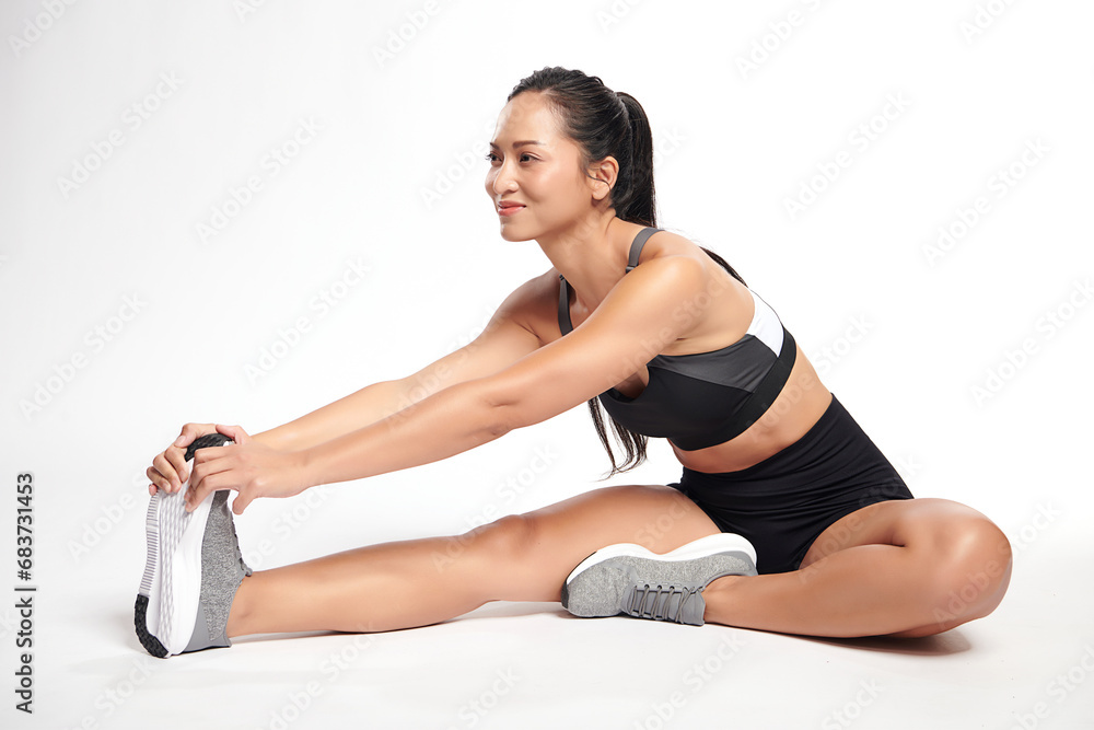 Obraz premium an asian woman is working out wearing the sport exercise suit with white background.