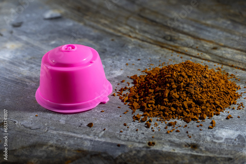 Reusable pink coffee capsule beside spilled coffee—eco-friendly solution for flavorful brews. Sustainable, convenient, and vibrant.