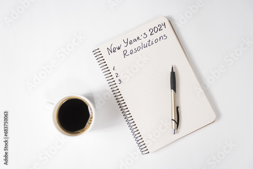 Phrase New Year's Resolutions 2024 in the notebook and pen. Cup of coffee on table