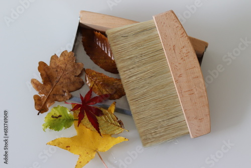 Kehrblech mit Herbstlaub und Handbesen