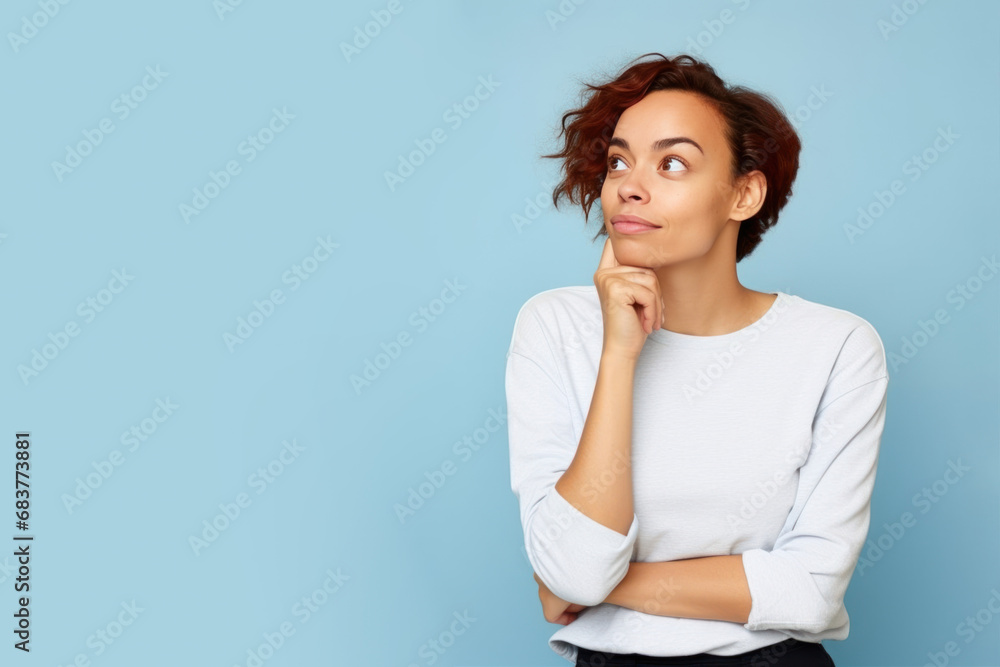 Jeune femme en train de penser en regardant sur le côté vers le haut, espace libre pour du texte ou mise en scène, tenue claire fond uni bleu pâle - obrazy, fototapety, plakaty 