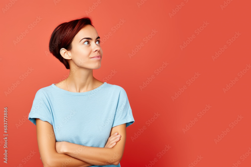 Jeune femme en train de penser en regardant sur le côté vers le haut, espace libre pour du texte ou mise en scène, tenue bleu clair fond uni rouge Jeune femme en train de penser en regardant sur le côté vers le haut, espace libre pour du texte ou mise en scène, tenue bleu clair fond uni rouge