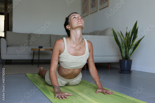 Young middle eastern woman practicing hatha yoga at home. Yogini doing the upward facing dog pose in her living room. Copy space, close up, interior background. photo