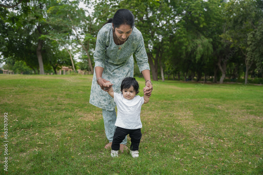 Young indian mother with her cute looking boy walking in garden, Teaching her boy to walk. Young indian mother with her cute looking boy walking in garden, Teaching her boy to walk.
