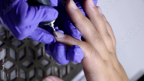 A vertical close up of manicurist treating a woman's cuticles using a manicure machine in a nail salon photo