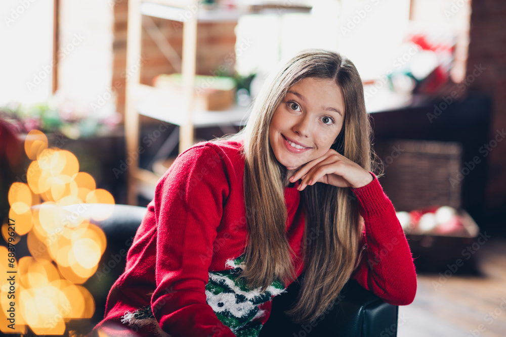 Fototapeta premium Photo of cute adorable schoolgirl with blond hairstyle wear red sweater sit on armchair hand on cheek staring at new year at home indoors