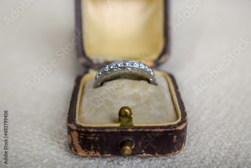 An opened antique / vintage 1920's brown leather ring case lined with yellow velvet and silk, with an antique platinum engagement ring with diamonds inside. 