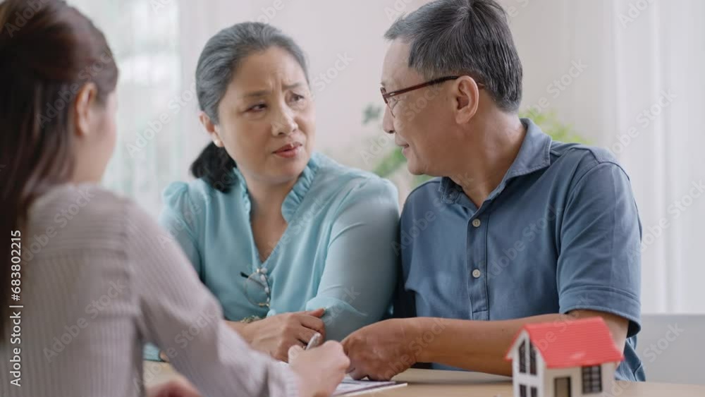 Asian mature couple thinking about buying real estate.Happy senior old aged woman and man customer landlord hold key to new house apartment,signing contract deal of loan pension mortgage at home. Asian mature couple thinking about buying real estate.Happy senior old aged woman and man customer landlord hold key to new house apartment,signing contract deal of loan pension mortgage at home.