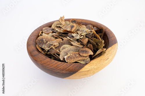 Heap of Senna alexandrina pods on a wooden plate isolated on a white background photo