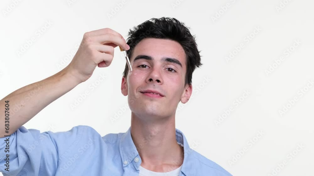 Focused man delicately dispenses facial lotion onto skin using a dropper, set against a backdrop of pristine white. His attentive eyes follow the droplet descent, ensuring precise application. Focused man delicately dispenses facial lotion onto skin using a dropper, set against a backdrop of pristine white. His attentive eyes follow the droplet descent, ensuring precise application.