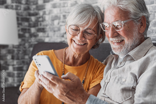 Elderly grandfather and grandmother spend time having fun using smartphone apps, middle-aged wife enjoy online entertainments, taking selfie with old husband, older generation and modern tech concept. photo