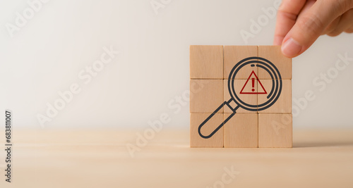 Risk analysis and management concept. Identify potential risks and develop strategies to mitigate. Wooden cube blocks with magnifying glass and triangle caution warning sign. VUCA management concept. photo