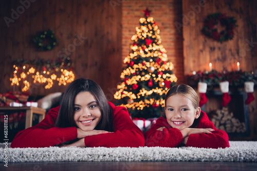 Photo of adorable cute small sisters wear red jumpers lying floor dreaming gifts indoors new year north pole house