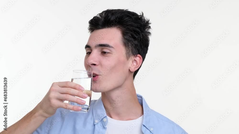 Satisfied Caucasian man takes a refreshing sip from a glass of water. His eyes reflect relaxation and pleasure, embodying the simple joy of quenching thirst. Satisfied Caucasian man takes a refreshing sip from a glass of water. His eyes reflect relaxation and pleasure, embodying the simple joy of quenching thirst.