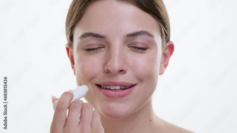 Caucasian woman gently applies hygienic lip balm, ensuring lips stay soft and moisturized. Against a pristine white backdrop, gesture exudes a sense of cleanliness and wellbeing. Caucasian woman gently applies hygienic lip balm, ensuring lips stay soft and moisturized. Against a pristine white backdrop, gesture exudes a sense of cleanliness and wellbeing.