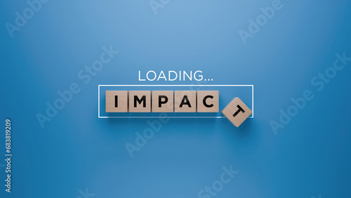 Fotografia Wooden blocks spelling 'IMPACT' with a loading progress bar on a blue background