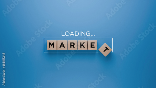 Wooden blocks spelling 'MARKET' with a loading progress bar on a blue background, economic trends and market growth concept