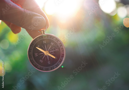 Hand holding compass with nature background. The concept of world tourism day, Searching the right directions and Travel photo