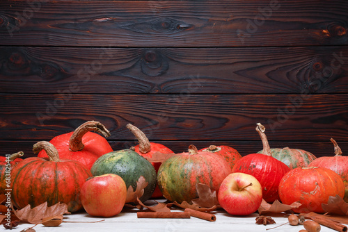 Fresh orange pumpkins and dry foliage side view with copy space on dark wooden barn wall. November Thanksgiving rustic background. Fall menu, holiday, harvest season