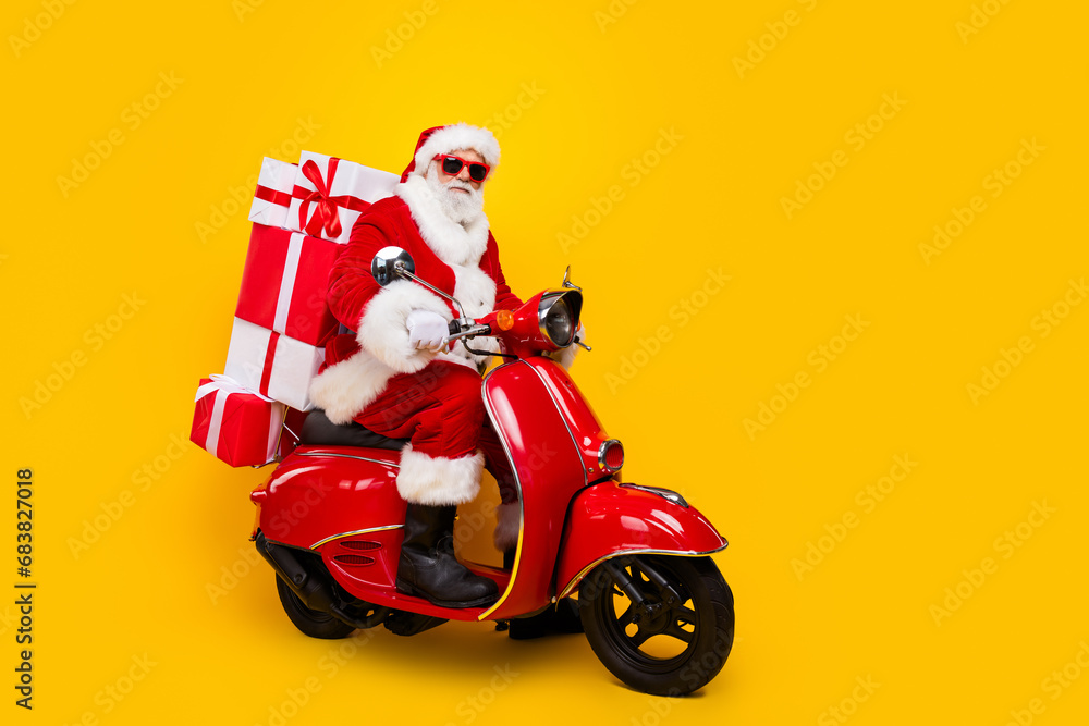 Full length photo of riding moped saint nicholas courier express new year delivery from north pole isolated on yellow color background Full length photo of riding moped saint nicholas courier express new year delivery from north pole isolated on yellow color background
