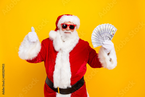 Photo of pensioner santa claus wear red traditional costume hold much money thumb up winner lottery isolated on yellow color background