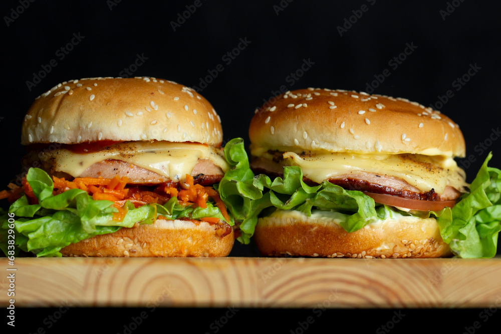 Two Fresh Sandwiches on a Wooden Cutting Board on a Dark Background Two Fresh Sandwiches on a Wooden Cutting Board on a Dark Background