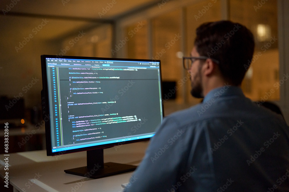 Busy smart business man software developer engineer programmer working late on pc computer in dark night office. Coder working with ai software development solutions. Back view, focus on screen. Busy smart business man software developer engineer programmer working late on pc computer in dark night office. Coder working with ai software development solutions. Back view, focus on screen.