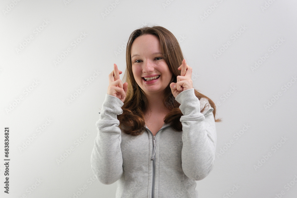 Waist-up shot of intense worried hopeful young woman waiting with anticipation for important result crossing fingers for good luck pursing lips from nervousness. looking faithfully