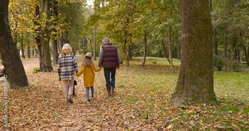 Small girl with grandparents on a walk in autumn forest