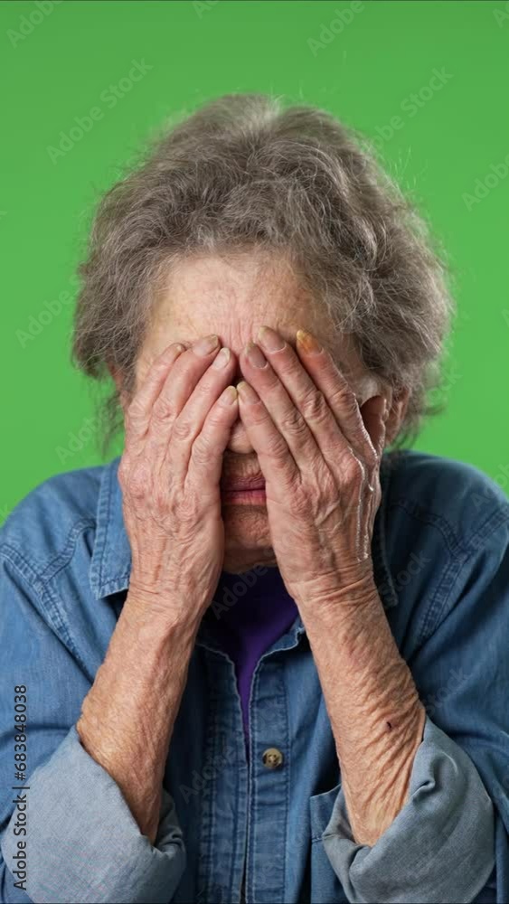 Vertical video portrait of afraid, troubled elderly senior old woman covering her eyes scared, with wrinkled skin and grey hair isolated on green screen background studio Vertical video portrait of afraid, troubled elderly senior old woman covering her eyes scared, with wrinkled skin and grey hair isolated on green screen background studio