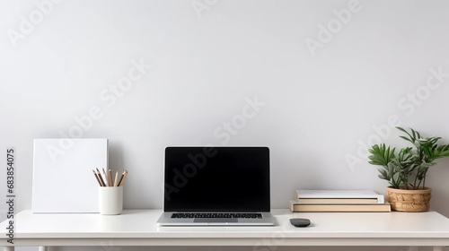 A clean, white minimalist workspace with a laptop, pens, and notebooks on the desk, and simple, uncluttered walls in the background. © Emil