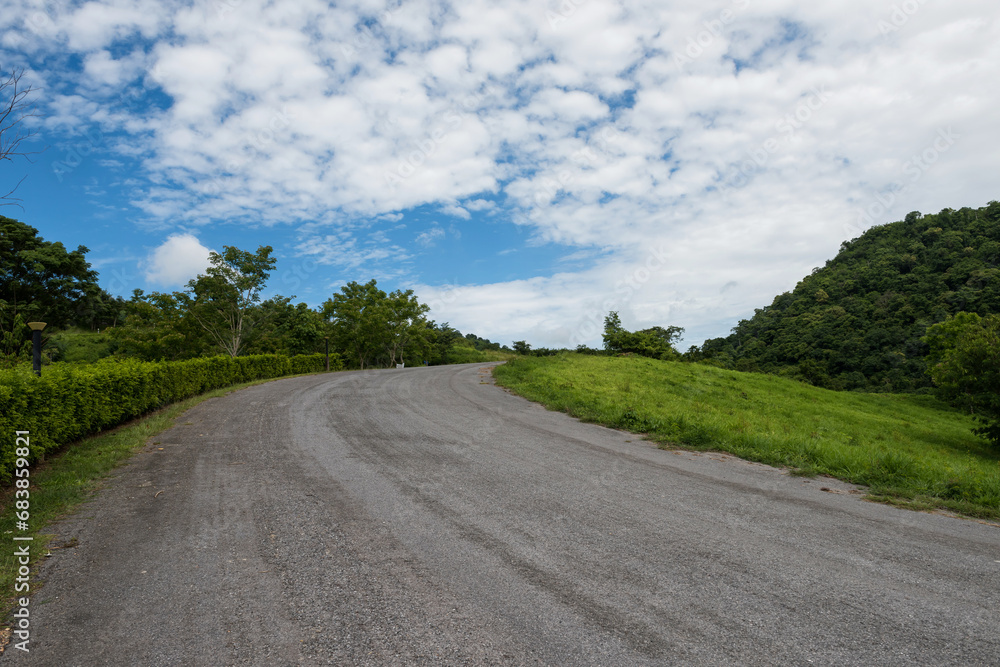 Uphill curve asphalt road against blue sky