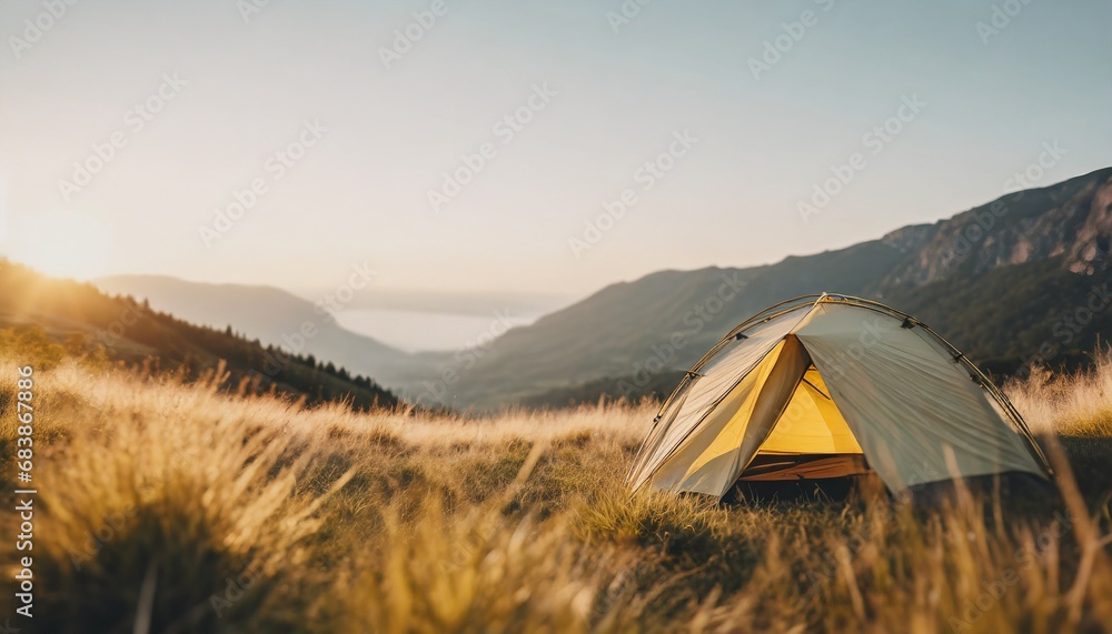 Camping in the wilderniss: Wonderful spot for heaving a calm night under the stars in the tent. Sunset scenery with golden light on the mountain in high grass.