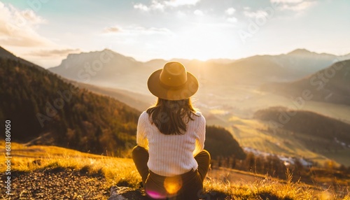 Young beautiful woman with hat sitting on mountain peak and enjoys the view into the valley. generative ai