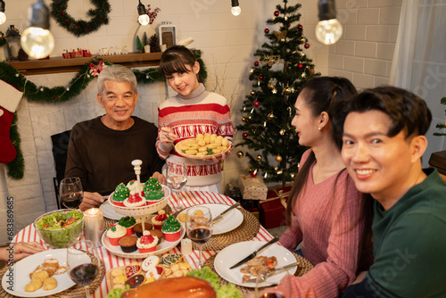 Happy Asia girl holding food with family celebrating Christmas in dinner at home