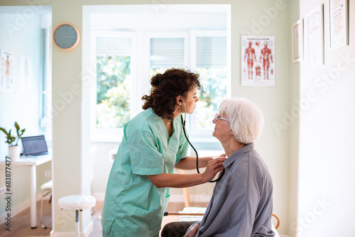 Female nurse using a stethoscope on a senior woman in the doctors office