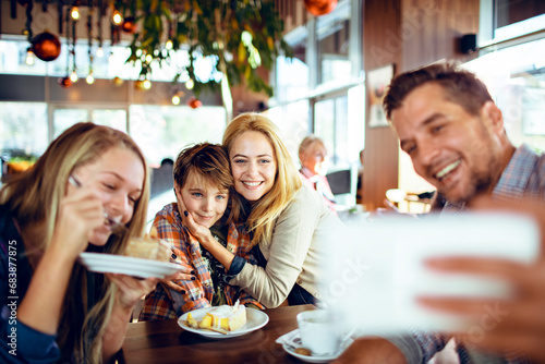 Young family taking selfie in cafe decorated for Christmas and the new year holidays photo