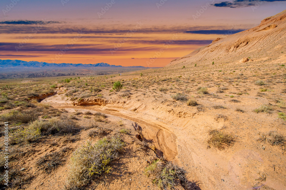 Enjoy the mesmerizing beauty of a desert sunset in the Red Bogut Mountains Witness the golden glow of the sun illuminating the jagged peaks Be captivated by the breathtaking awe inspiring spectacle