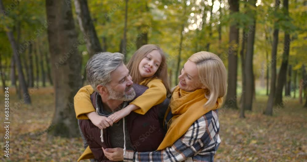 Grandfather holding granddaughter piggyback in autumn park Grandfather holding granddaughter piggyback in autumn park