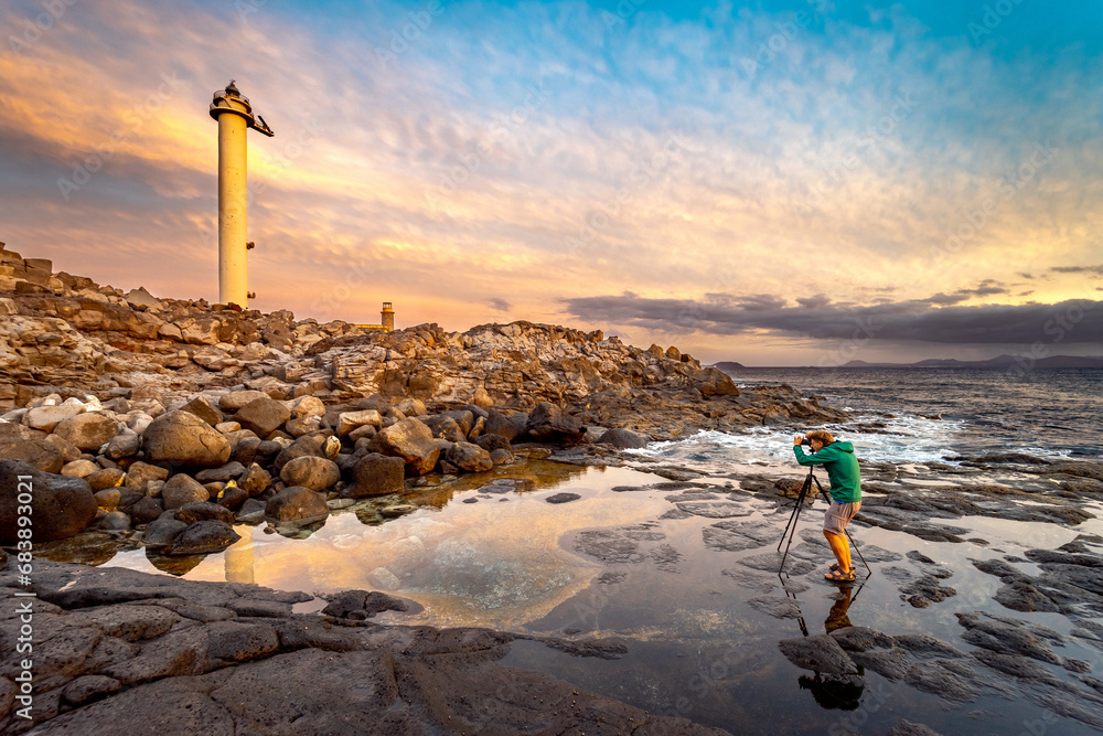 Golden lighthouse captured by photographer at sunset - obrazy, fototapety, plakaty 