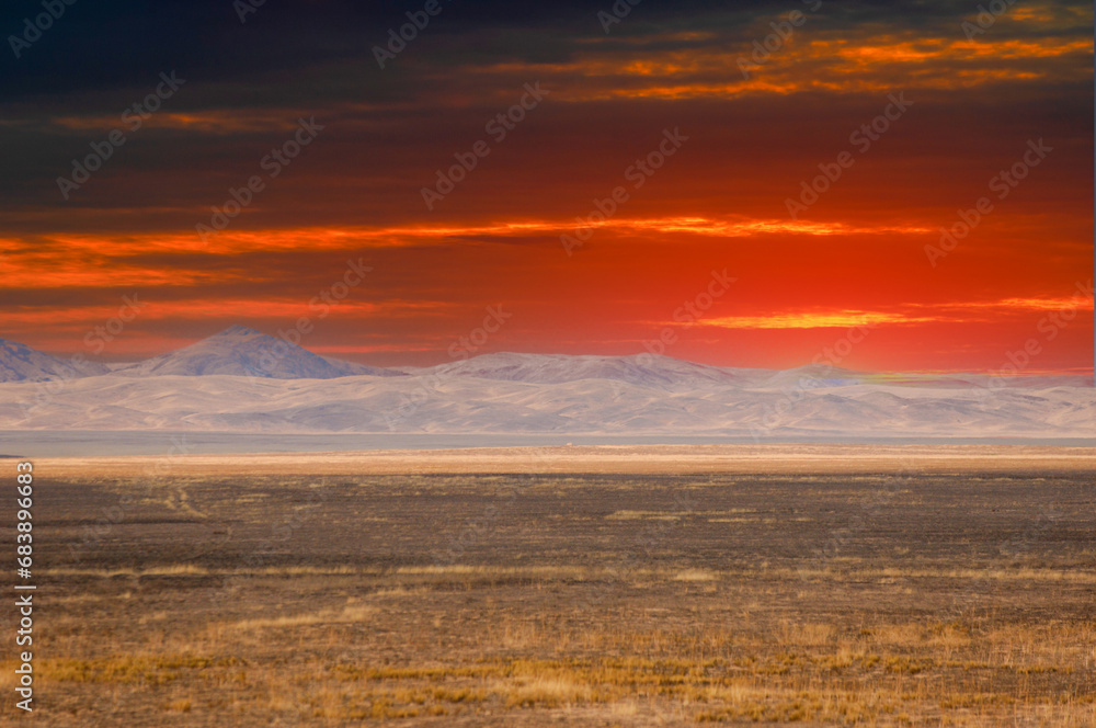 Steppe, prairie, plain, Nature's exquisite masterpiece reveals itself as the scorching sun descends beneath the endless dunes, leaving behind a breathtaking spectacle of warm hues. Sunset Serenity