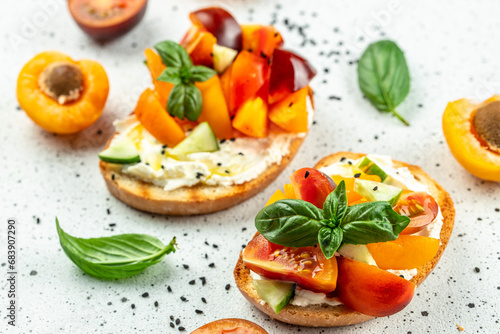 Gourmet sandwiches bread toast, bruschetta with cream cheese, peaches, tomatoes and green basil leaves