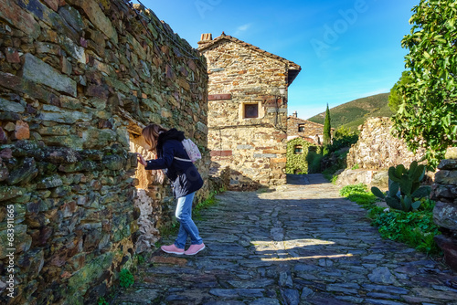 Woman leaning out of a window of an old stone house in the village of Patones de Arriba, Madrid. photo