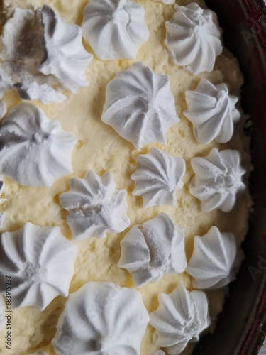 A large piece of multi-layer cake with cherries and a meringue decoration