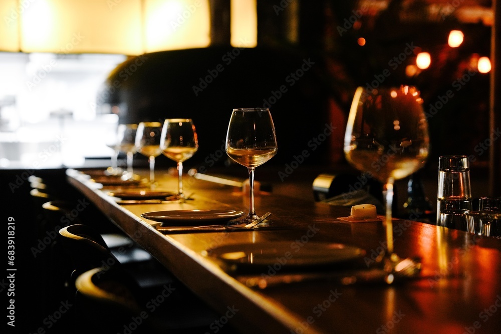 long bar table with line of chairs and wine glasses next to each chair with warm light vibe