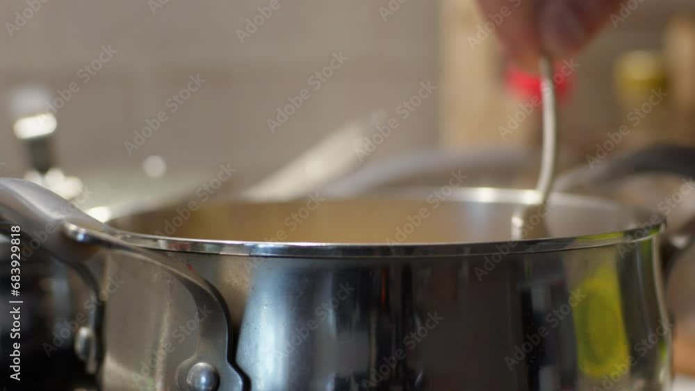 A Shiny Silver Spoon Stirring Delicious Soup in a Steamy Pot A Shiny Silver Spoon Stirring Delicious Soup in a Steamy Pot