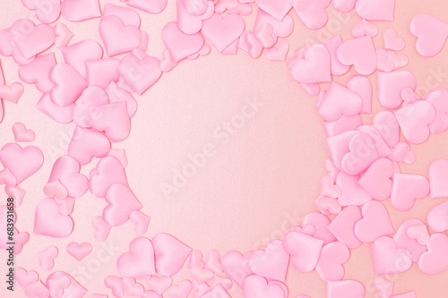 Round frame made of textile pink confetti in a heart shape on a glittering background. Monochrome concept with place for text.