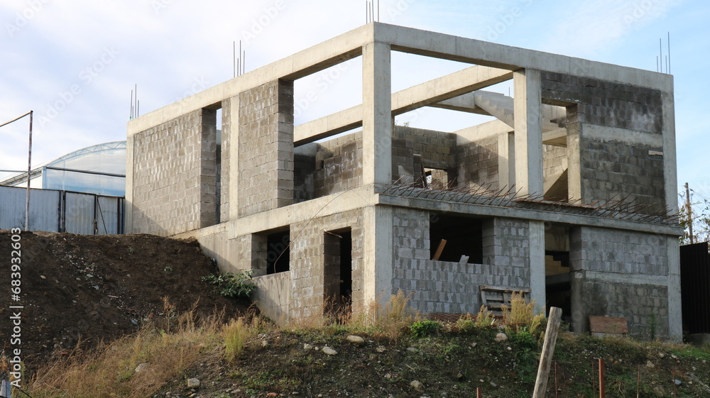 Fototapeta premium box of a two-story cottage under construction without a roof, a block building at the stage of erecting walls, construction of a residential building in a suburban area