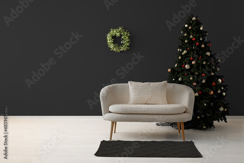 Beautiful Christmas tree with comfortable sofa near dark wall. Banner for design photo