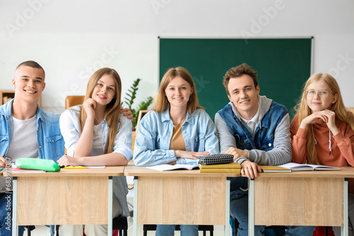 Happy classmates sitting at...
